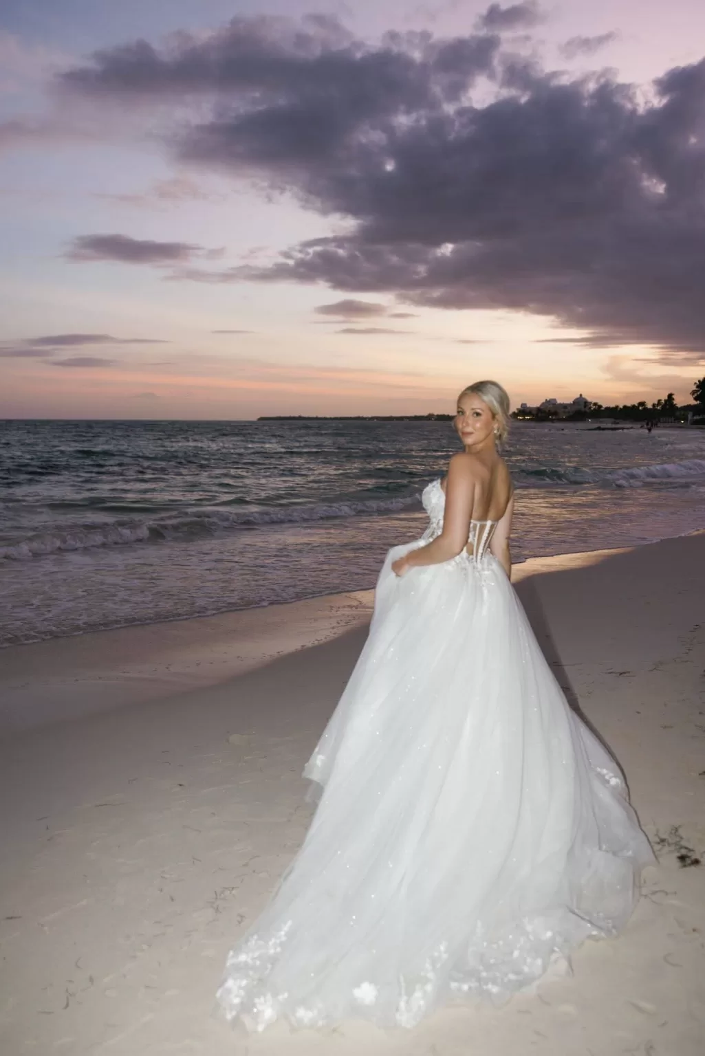 Bride looking over her shoulder on the beach at golden hour at Villa La Joya.