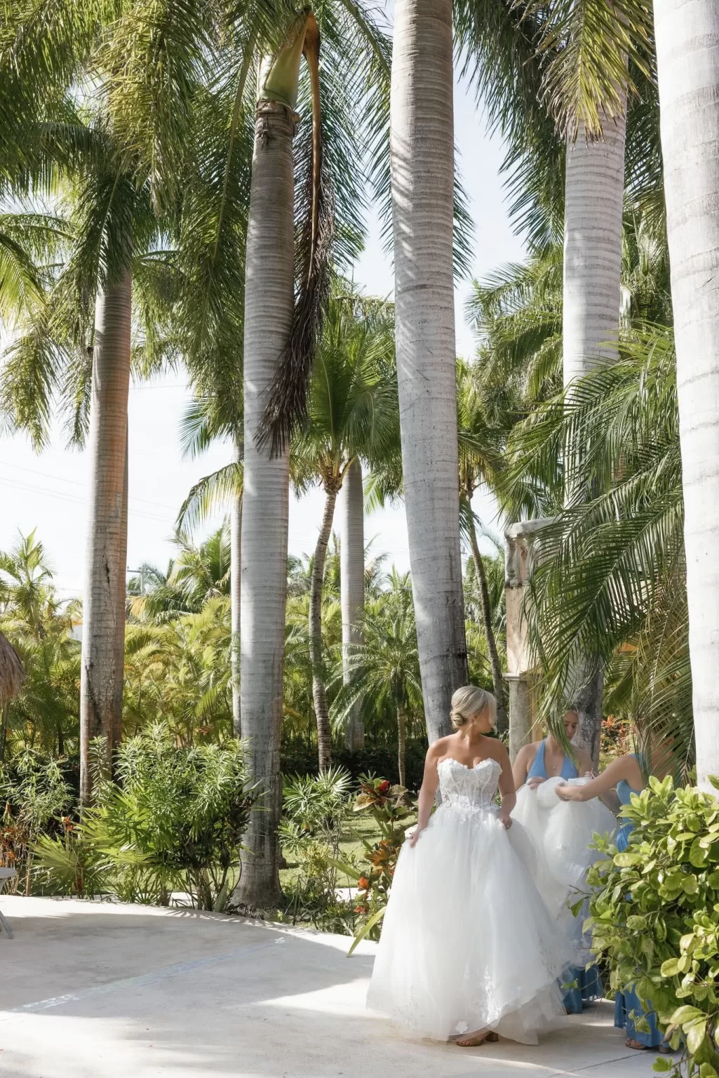 Bride in her wedding gown stands among tropical palm trees in the garden at Villa La Joya