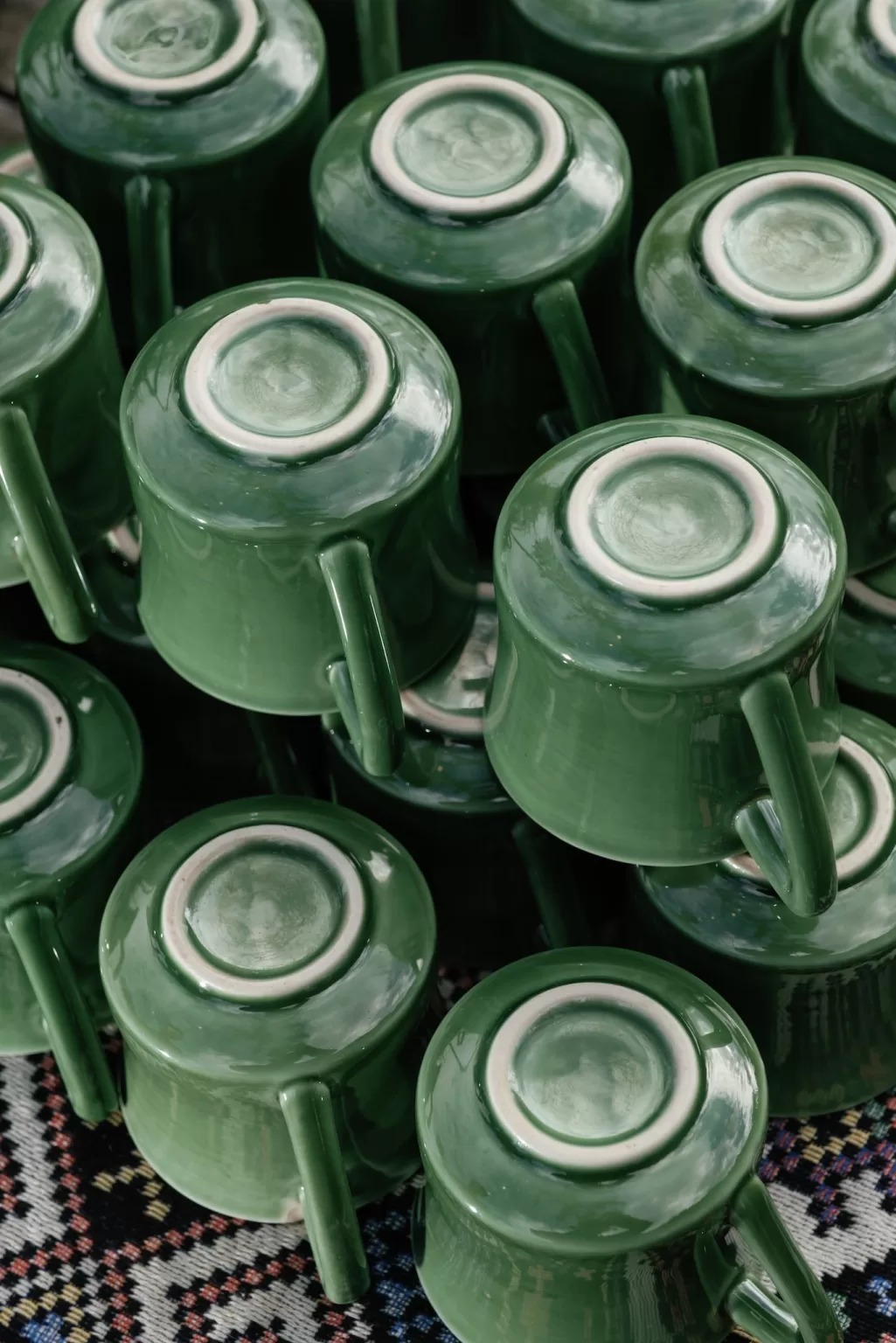 Close-up of stacked green ceramic cups arranged upside down on patterned fabric during wedding preparations at Ville de Mont Mountain Resort.