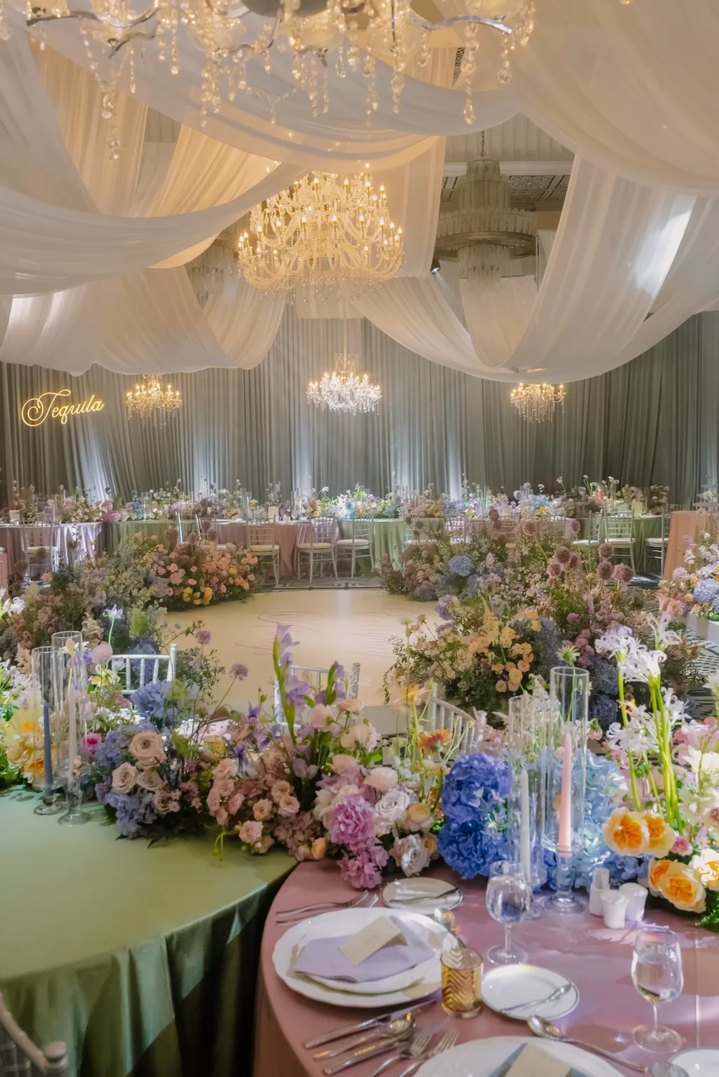 Luxurious wedding reception design at Ville de Mont Mountain Resort featuring cascading florals, pastel tables and glowing chandeliers beneath draped ceilings.