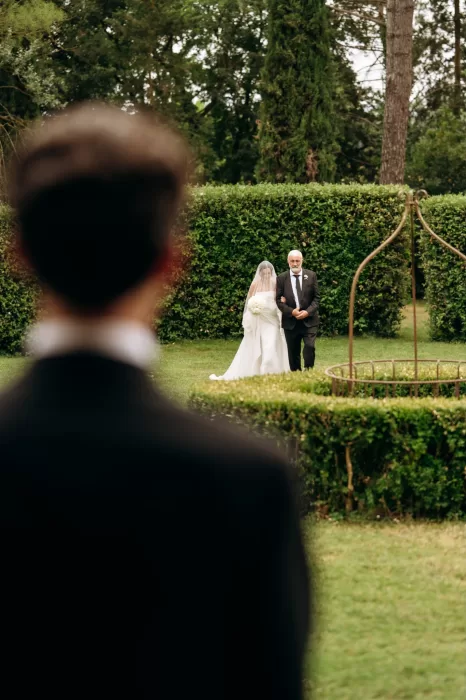 Bride walking down garden aisle with father as guests wait at Castello di San Fabiano