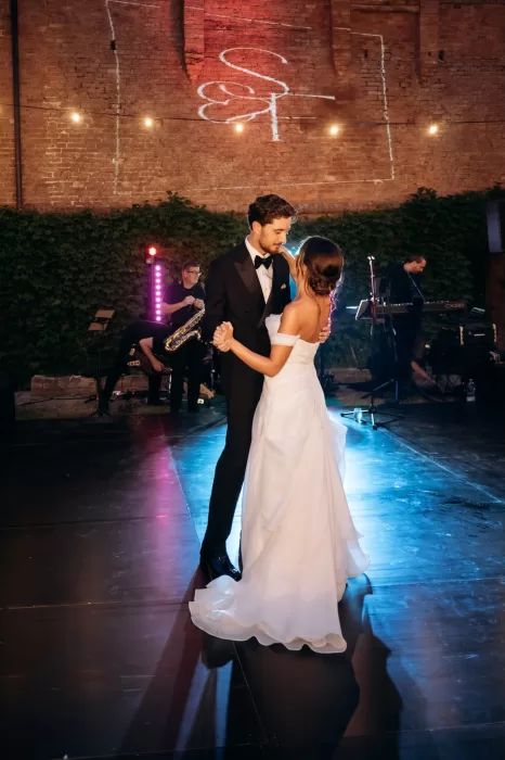 Couple sharing first dance surrounded by guests and warm lights at Castello di San Fabiano