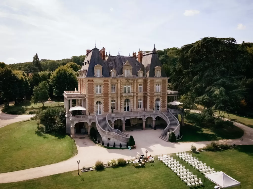 Aerial view of Château Bouffémont with outdoor ceremony chairs arranged on the lawn in front of the grand façade.