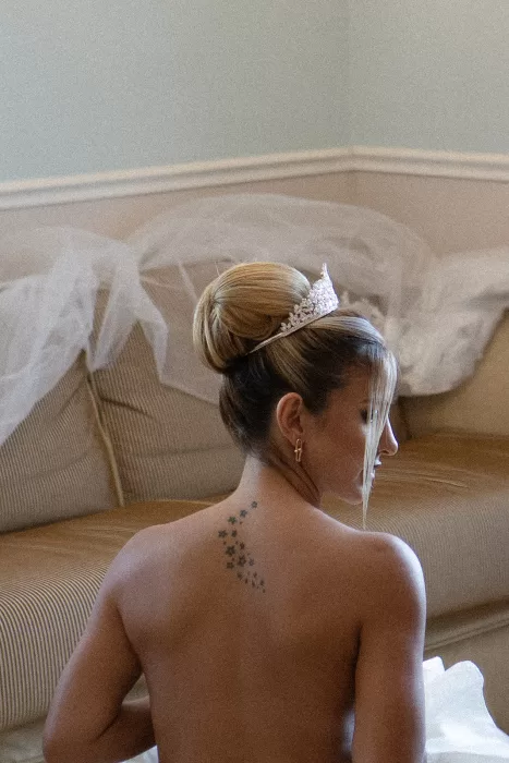 Bride with an elegant updo and sparkling tiara sitting softly lit indoors at Château Bouffémont.