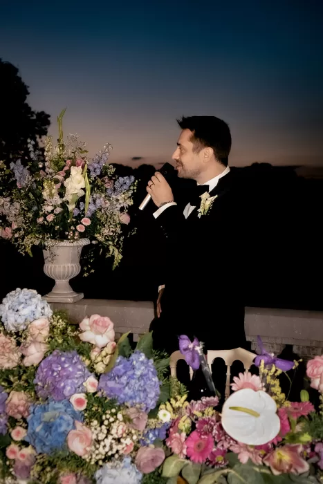 Groom giving a speech at sunset on the terrace of Château Bouffémont, surrounded by pastel floral arrangements.