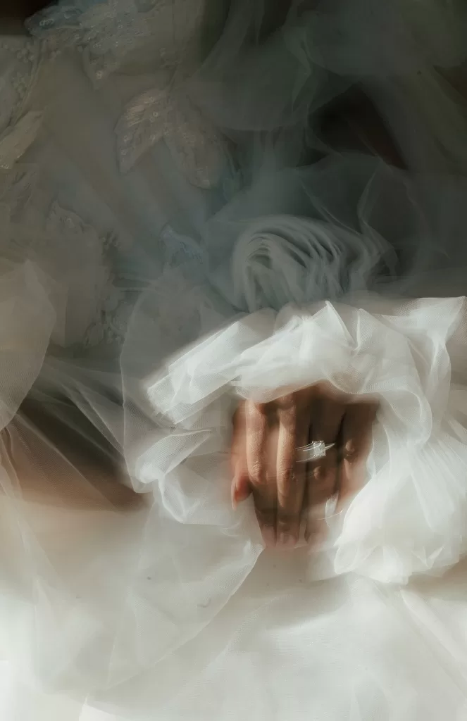 Close-up of the bride’s hand with engagement ring resting on soft layers of tulle from her wedding gown at Common Goods.