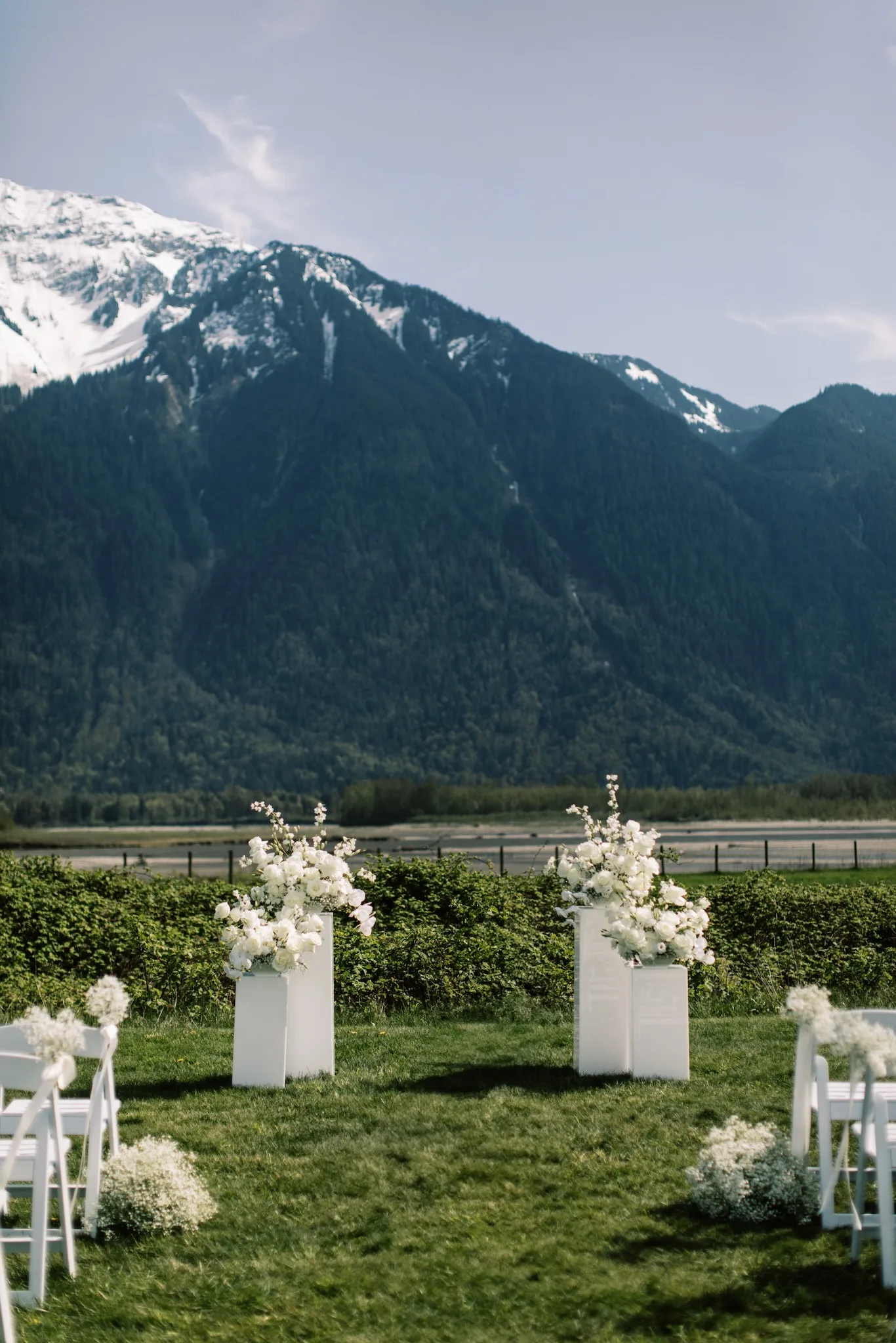 Outdoor ceremony setup with white florals and mountain backdrop at Fraser River Lodge