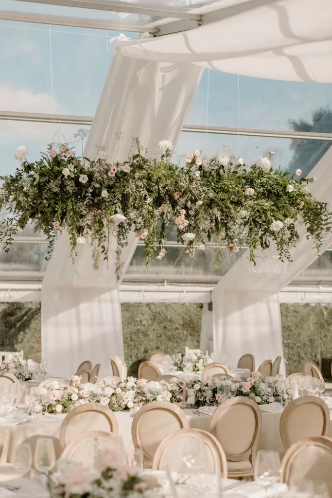 Wedding table with candle, glassware and table number surrounded by soft florals at Hotham Hall Estate