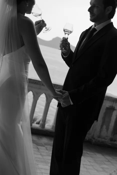 Black and white moment of couple toasting with champagne overlooking Lake Garda at Isola del Garda