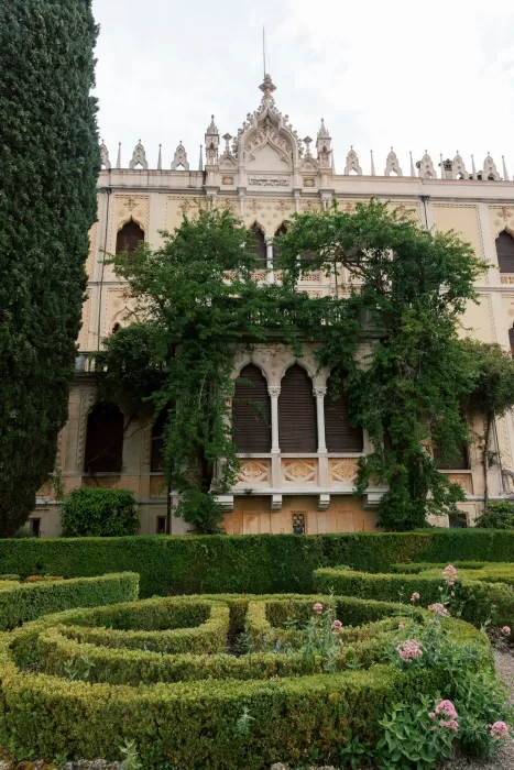 Villa facade partially covered in greenery with manicured gardens at Isola del Garda