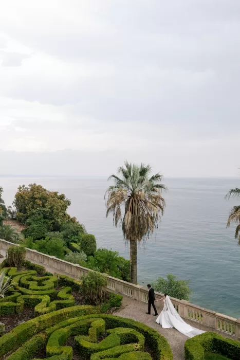 Bride and groom walking along garden terrace overlooking Lake Garda at Isola del Garda