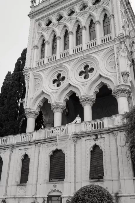 Bride standing on balcony with long veil cascading down facade at Isola del Garda