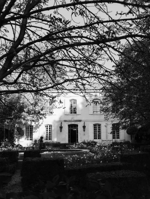 Black and white view of Mas de Chabran gardens with fountain and formal hedges.