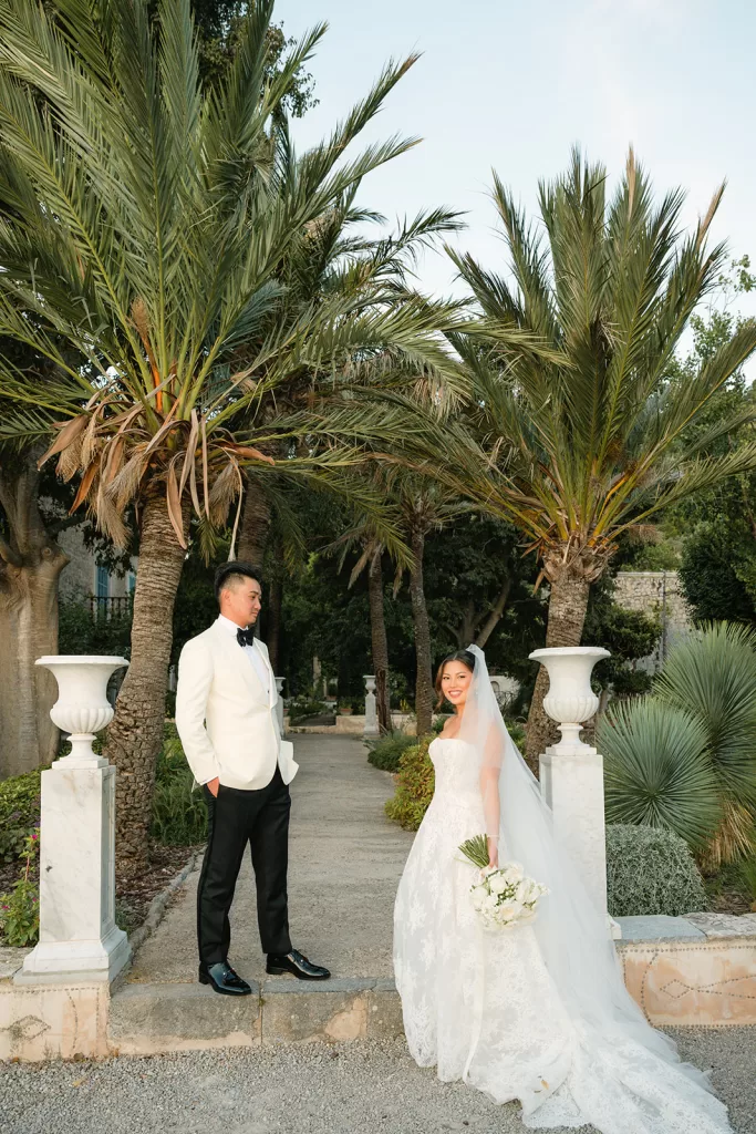 Bride and groom posing in a garden at Son Marroig surrounded by palms and Mediterranean greenery