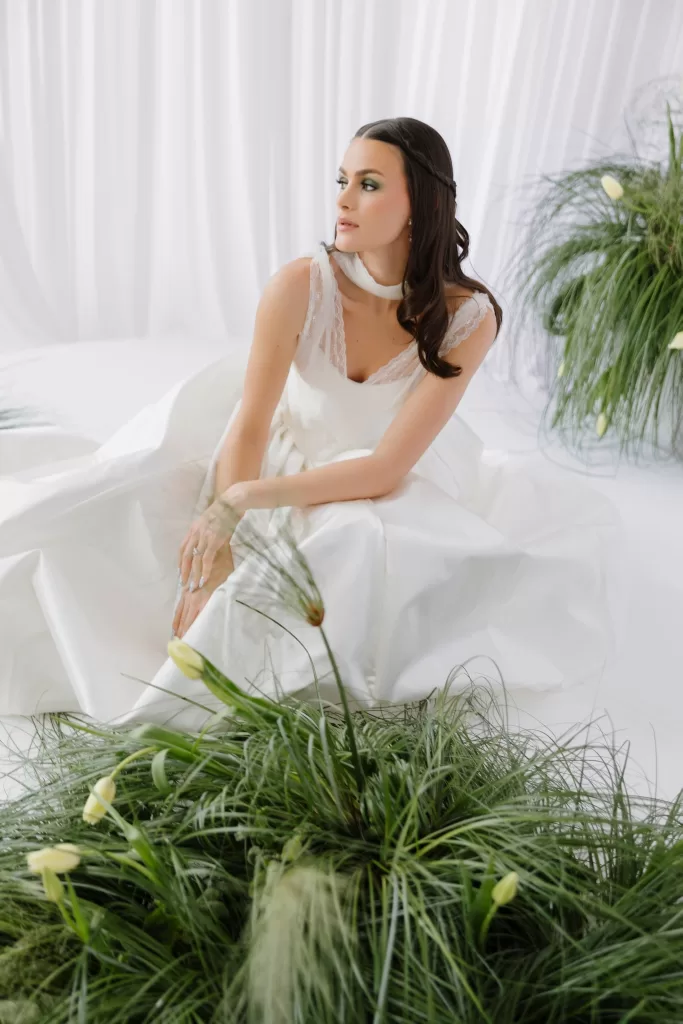Bride seated in structured gown surrounded by soft greenery and tulips at Studio Sunset Chicago