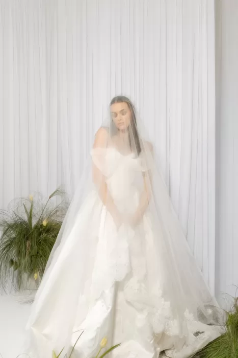 Bride in voluminous gown framed by sheer drapes and minimal floral installation at Studio Sunset Chicago