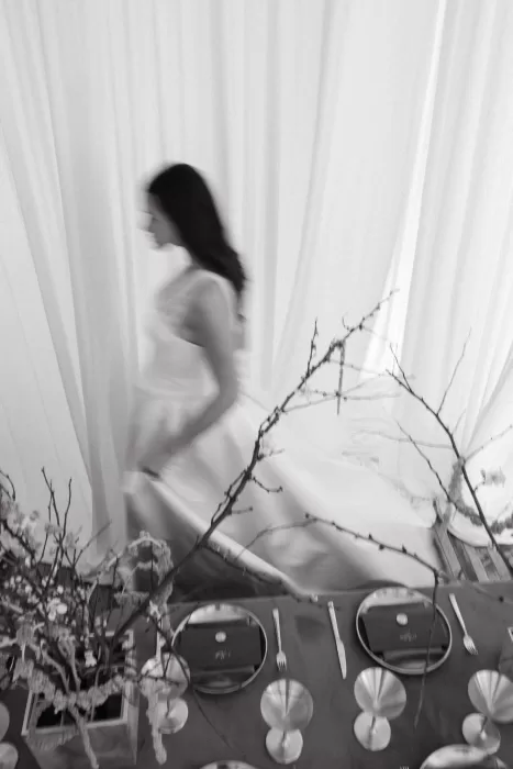Blurred bride moving past styled reception table with sculptural branches and metallic place settings at Studio Sunset Chicago