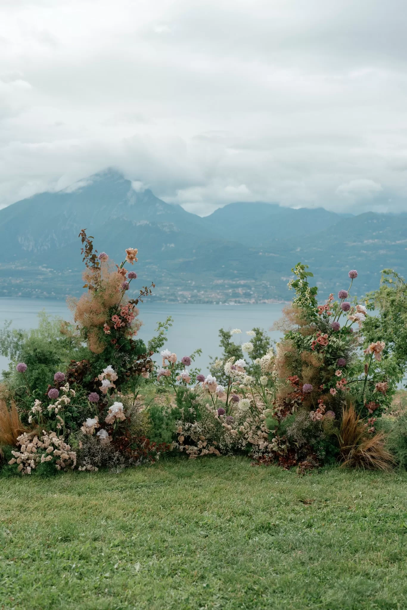 Romantic floral ceremony installation overlooking a lake and mountains at an outdoor destination wedding.