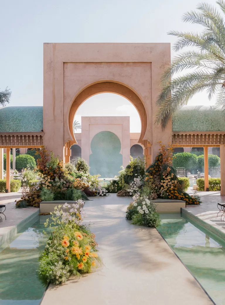 Wedding ceremony set beneath Amanjena’s iconic arches with layered florals, reflective pools and soft afternoon light.
