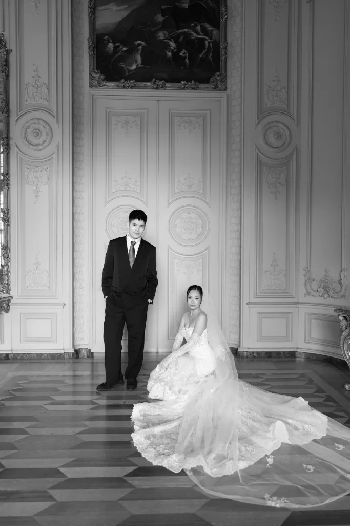 Bride seated with long train while groom stands beside her in an ornate palace room, photographed by Buluntu Weddings