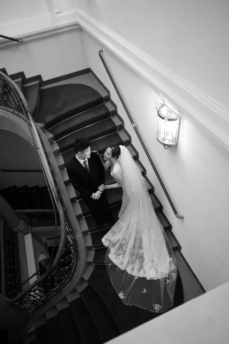 Groom gently holding bride as she looks away in a softly lit historic room