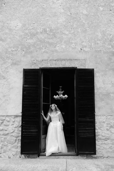 Bride standing in open window with shutters at Finca Morneta