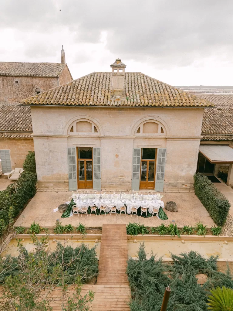 Aerial view of an outdoor wedding reception in the Fontsanta courtyard with long tables and Mediterranean architecture.