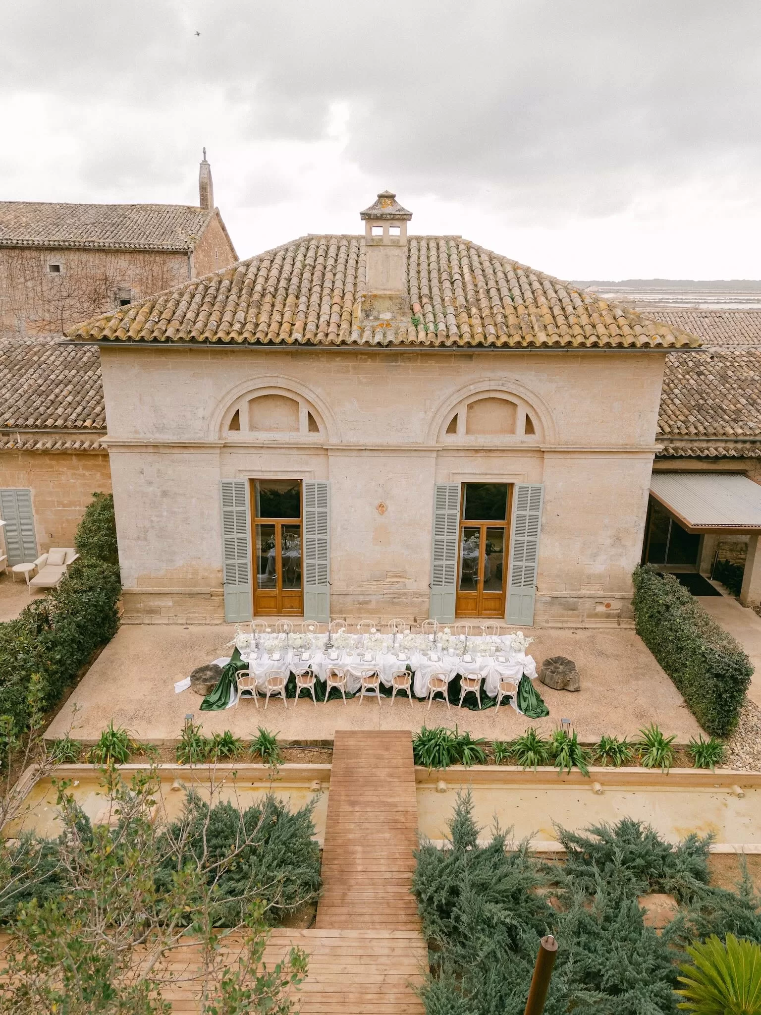 Aerial view of an outdoor wedding reception in the Fontsanta courtyard with long tables and Mediterranean architecture.