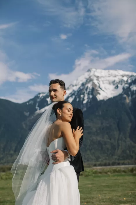 Bride and groom embracing with mountain views behind at Fraser River Lodge