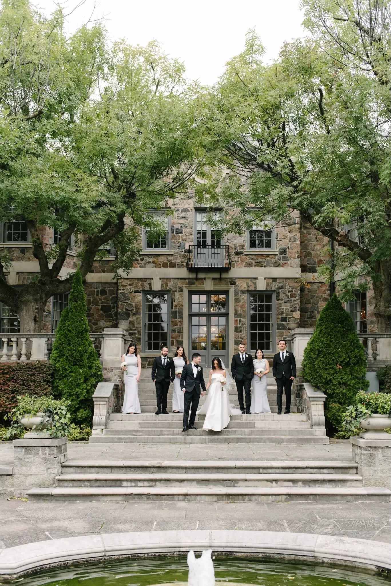 Bride and groom with their wedding party standing on the stone steps of Graydon Hall.