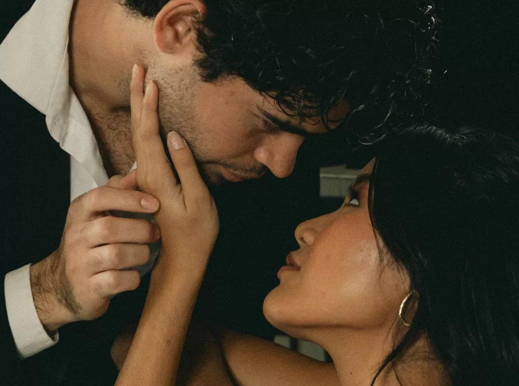 Close-up portrait of the couple in a softly lit, cinematic moment.