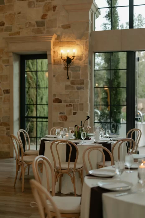 Softly lit reception tables with neutral linens and delicate florals in stone-walled space