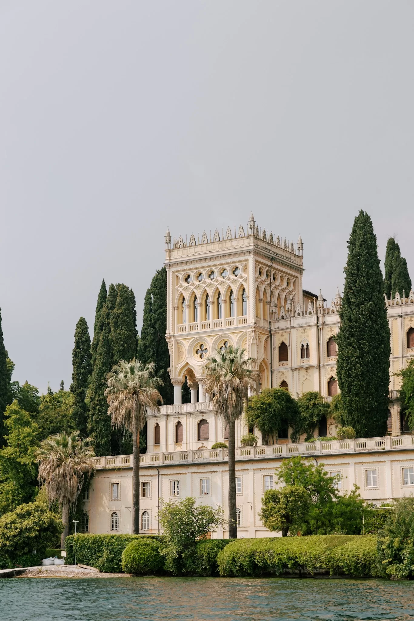 Grand lakeside view of Isola del Garda villa surrounded by lush greenery and water