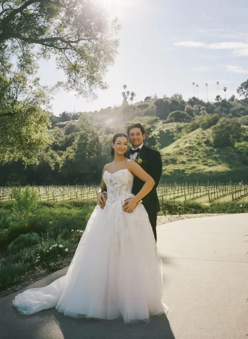 Newlyweds pose in soft sunlight overlooking the vineyards at Monserate Winery