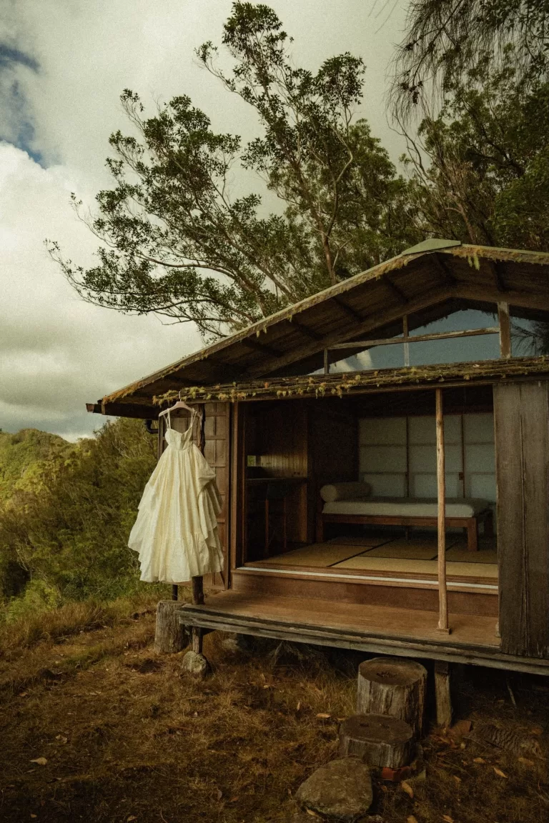 Wedding dress hanging outside the rustic wooden structure of Ossipoff’s Cabin, framed by trees and soft daylight.