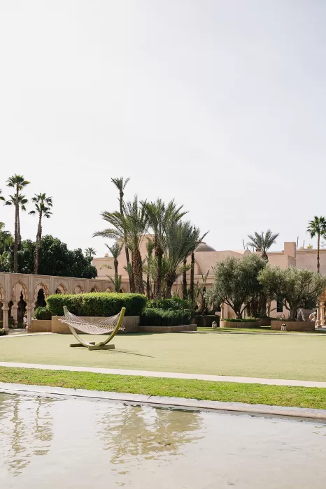 Minimalist hammock set on manicured lawn with palm trees at Palais Namaskar