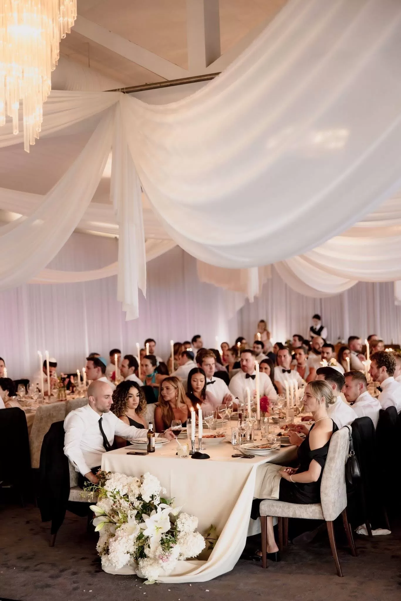 Guests seated under draped white fabric and candlelight at Sergeants Mess reception.