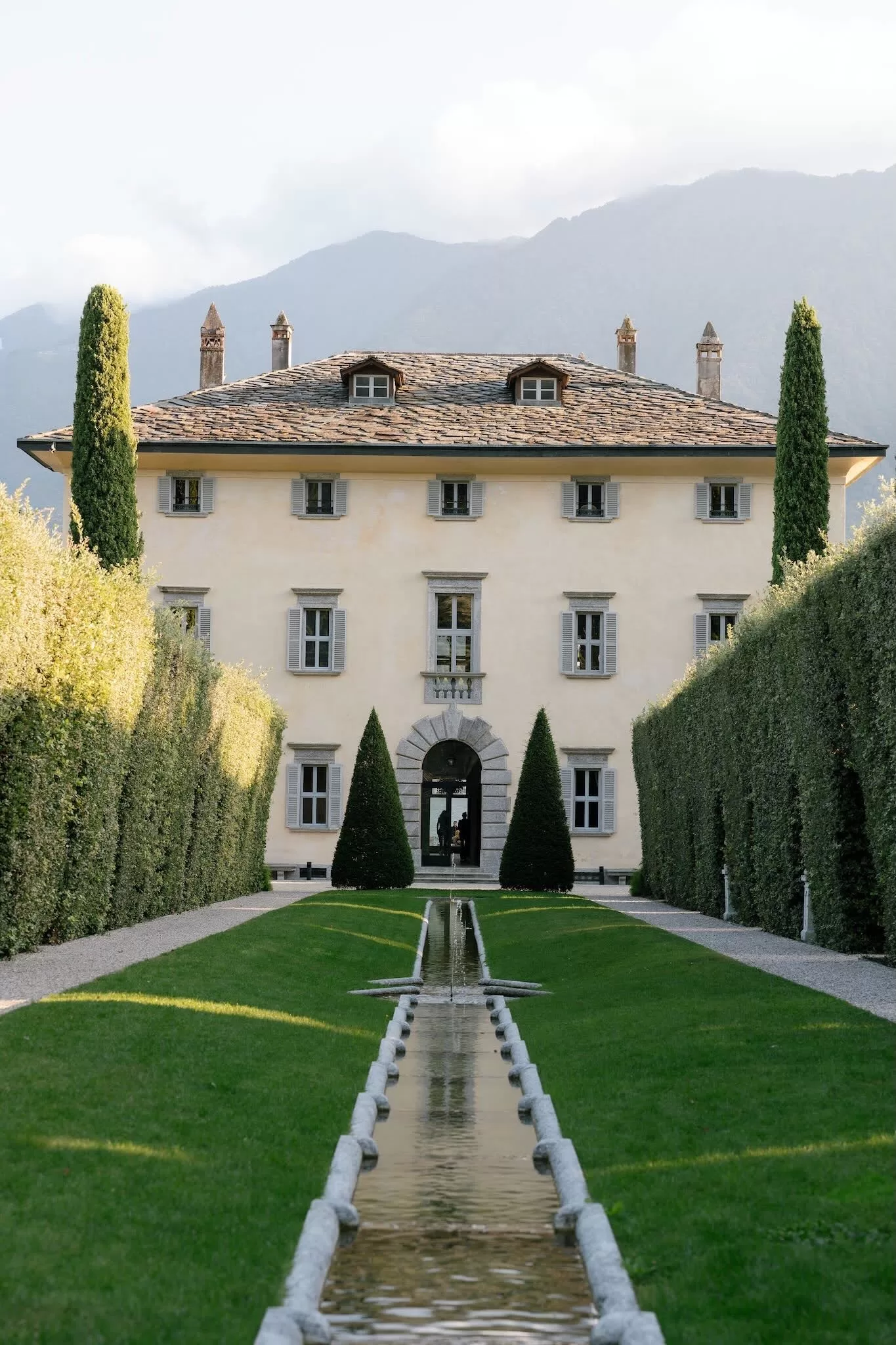 Manicured garden pathway with reflective water feature leading to Villa Balbiano.