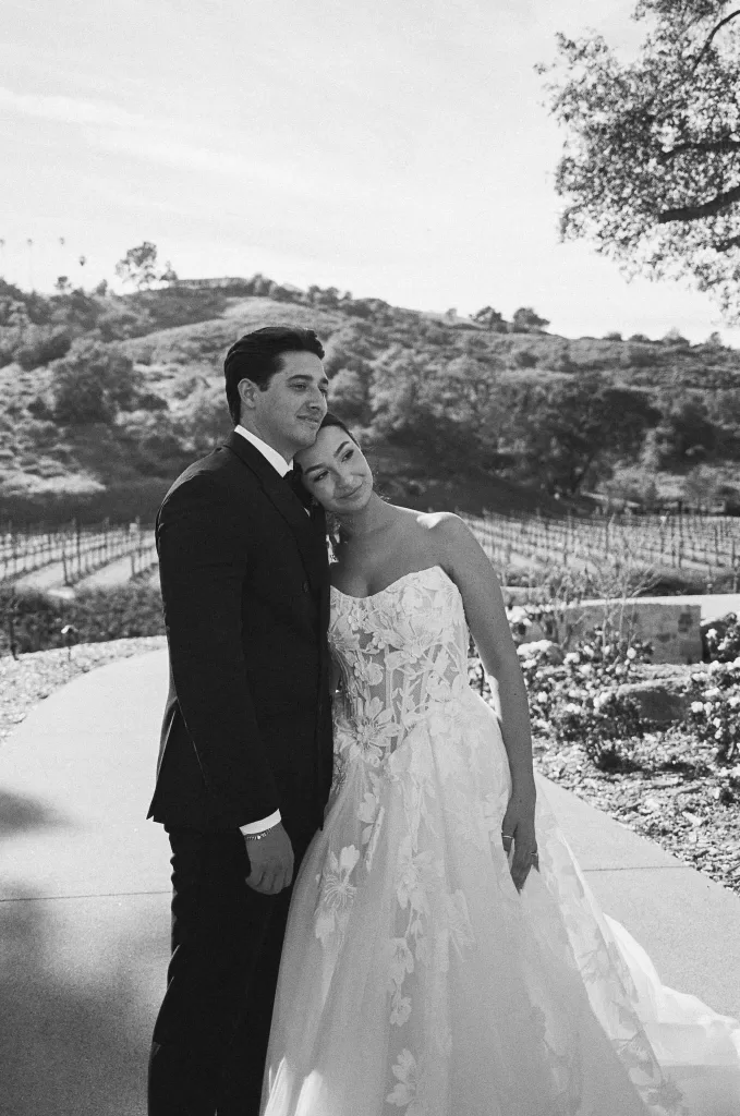 Bride and groom pose together on a sunlit path overlooking the San Diego vineyards