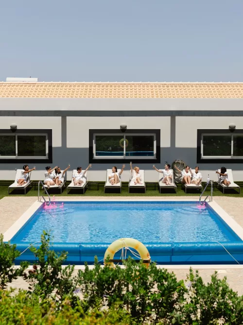 Bridesmaids lounging beside the pool in matching robes before the ceremony.