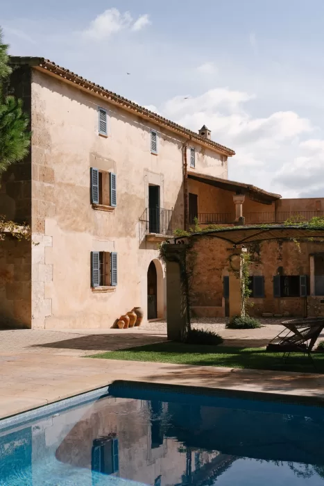 Sunlit courtyard with pool reflecting the finca’s stone façade and Mediterranean surroundings