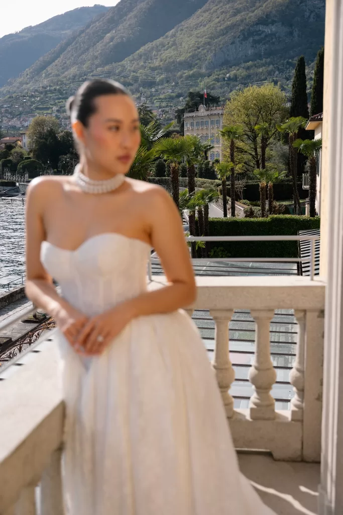 Bride softly framed on the balcony, with Hotel Villa Marie and Lake Como behind her.