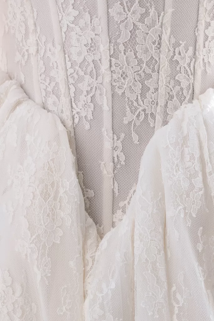 Close-up of delicate lace embroidery on the bride’s wedding dress bodice.