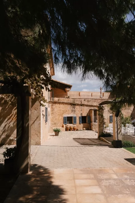 Warm stone courtyard at a Mallorca finca with shutters, greenery, and soft Mediterranean light