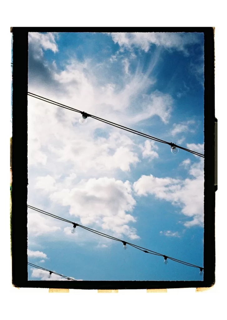 Blue sky framed with festoon lights, creating a relaxed outdoor wedding atmosphere
