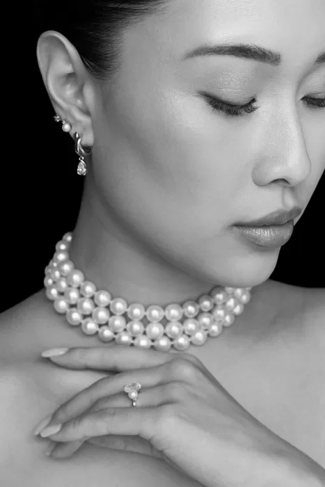 Close-up of pearl bridal jewellery, glowing makeup, and delicate drop earrings.