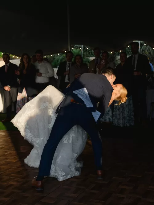 Bride and groom sharing a dramatic first dance kiss beneath the evening tent.