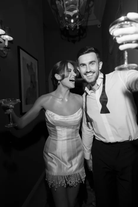 Bride and groom raising champagne glasses during their wedding reception in black and white