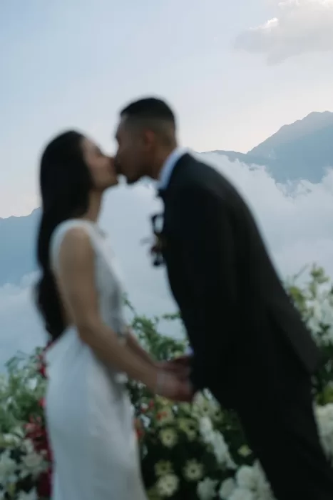 An intentionally soft-focus portrait of the couple kissing against a pale mountain horizon.