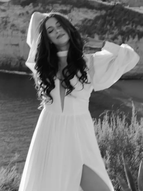 Black and white portrait of the bride by the Algarve cliffs with wind moving her veil